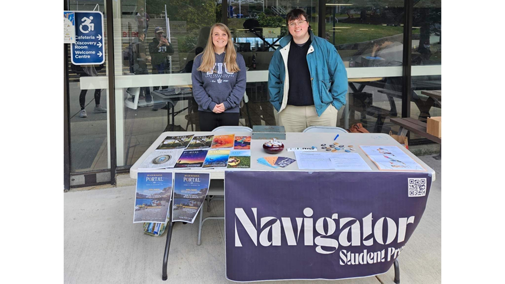 Portal 2023 Masthead selling launch tickets outside the cafeteria with The Nav / Left to right: Portal 2023 Fiction Editor Liz Baltzer, Nav Managing Editor Sean Desrochers